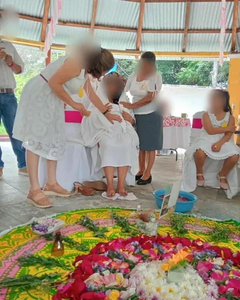 Un Blessing Way: la mamá sentada, de blanco, rodeada de su círculo, frente a un mandala de flores en el piso