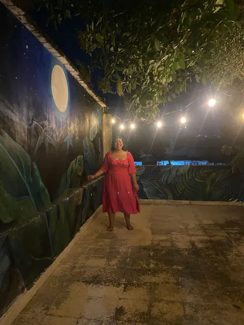 Tanis de vestido rojo, de noche, en la terraza iluminada con focos
