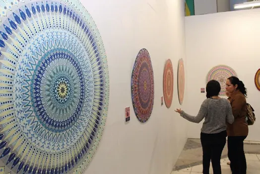 Dos visitantes miran sus mandalas colgados en la sala de una exposición
