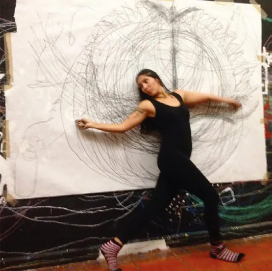 Tanis dibujando con los brazos extendidos sobre un papel de gran formato, en un performance