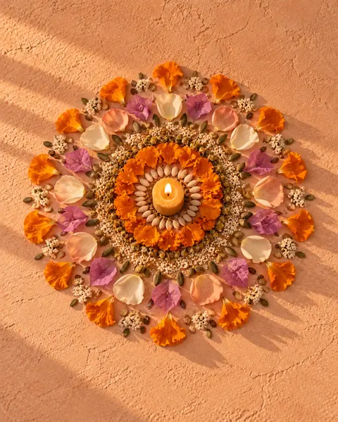 Un mandala de pétalos de cempasúchil, rosa y buganvilia armado en el suelo
