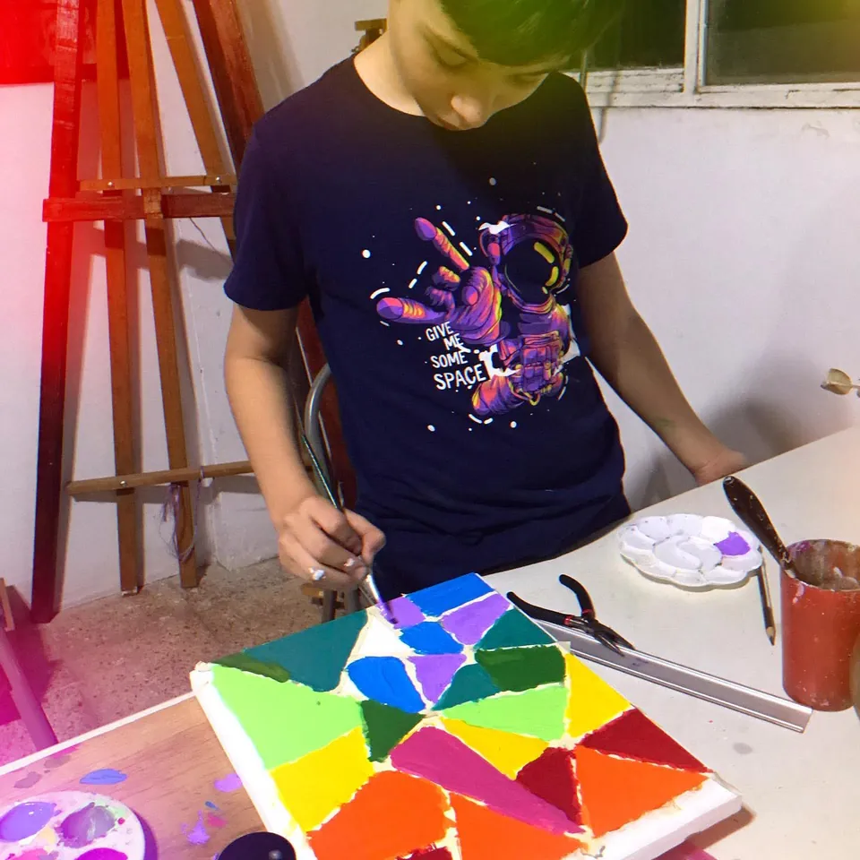 Un niño pinta un cuadro de geometría en colores brillantes en el taller