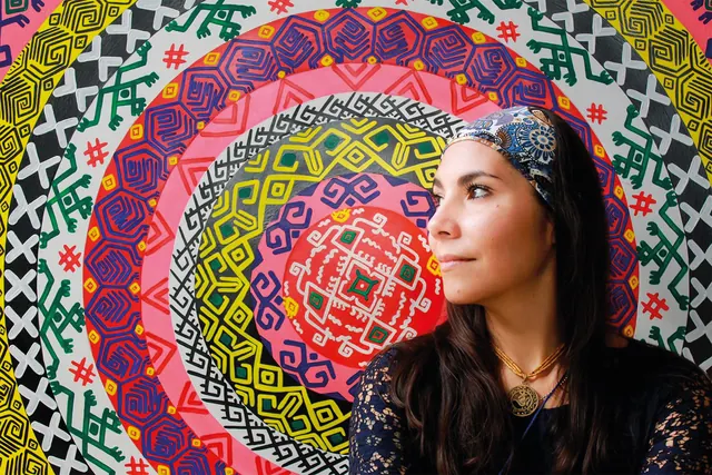 Tanis sonriendo frente a uno de sus mandalas de Cartografía de lo sagrado, con un pañuelo en el pelo