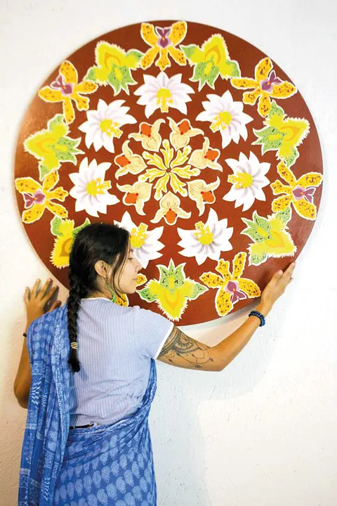 Tanis, de sari azul, pintando un mandala de flores más grande que ella