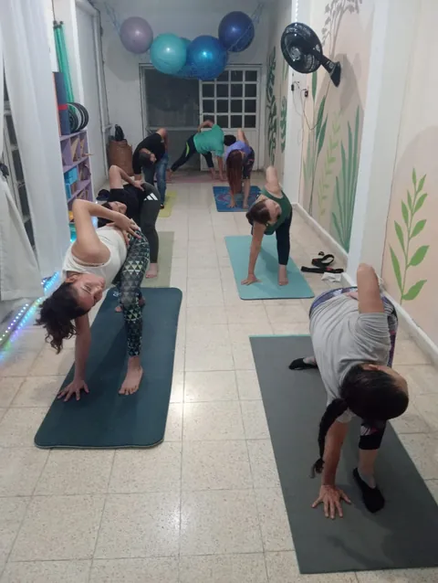 Una clase de yoga en el salón del mural: alumnas en sus tapetes, en una torsión